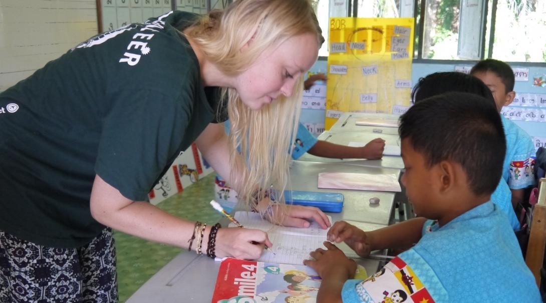 Projects Abroad volunteer teaching in Thailand marks the classwork of a young student. A volunteer corrects the work of her students during her teaching work experience in Thailand.
